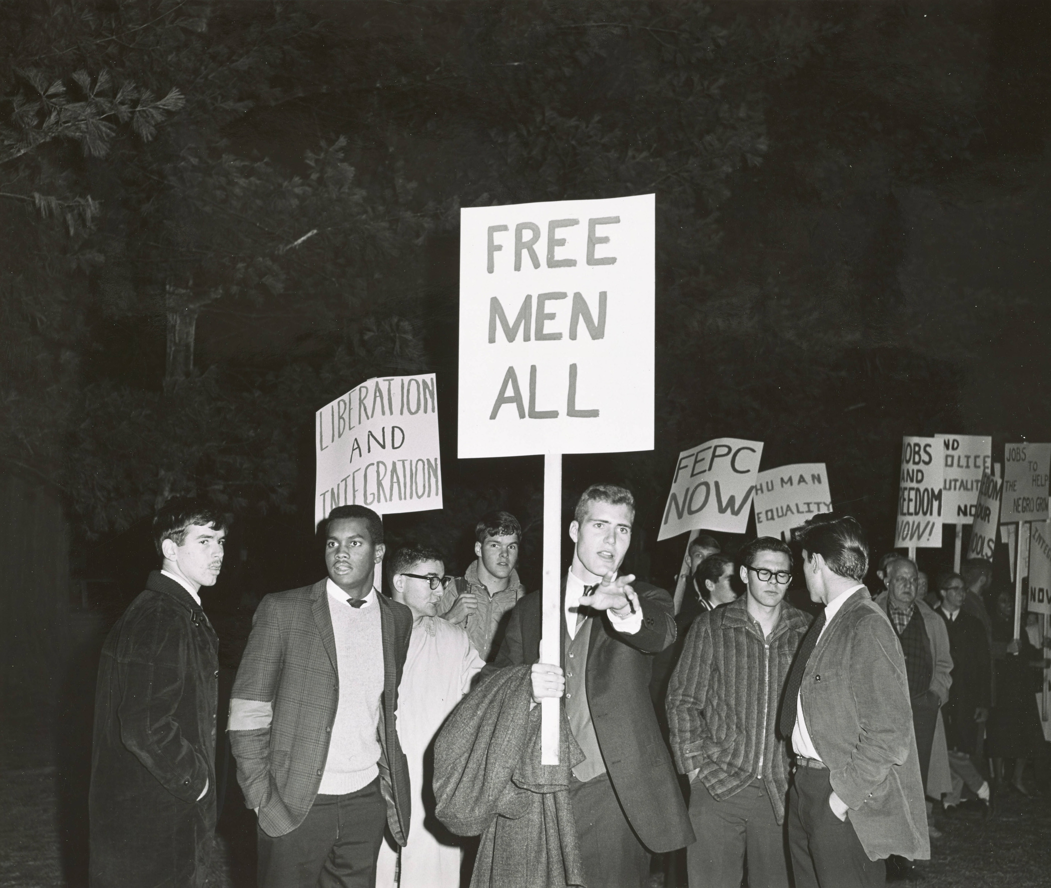 Protestors hold signs reading “Free Men All” and “Liberation and Integration,” 1963