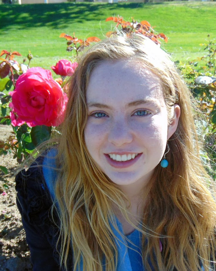 Mia Nelson, the Fall 2019 Historical Accountability Student Research Fellow, sits in front of pink rose bushes.