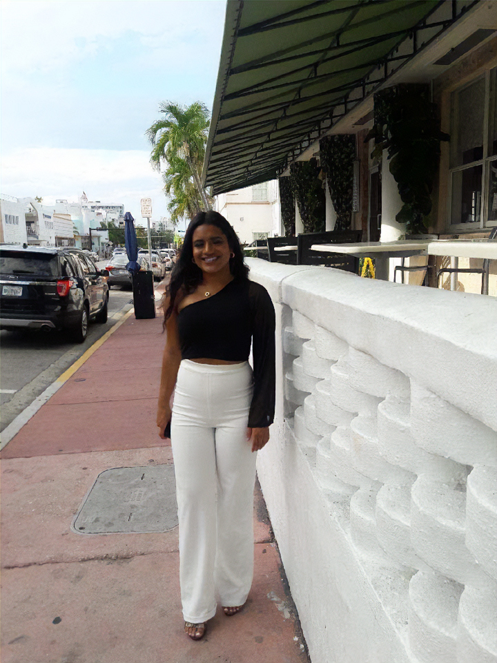 Rachel Perez stands on the sidewalk of a busy street.