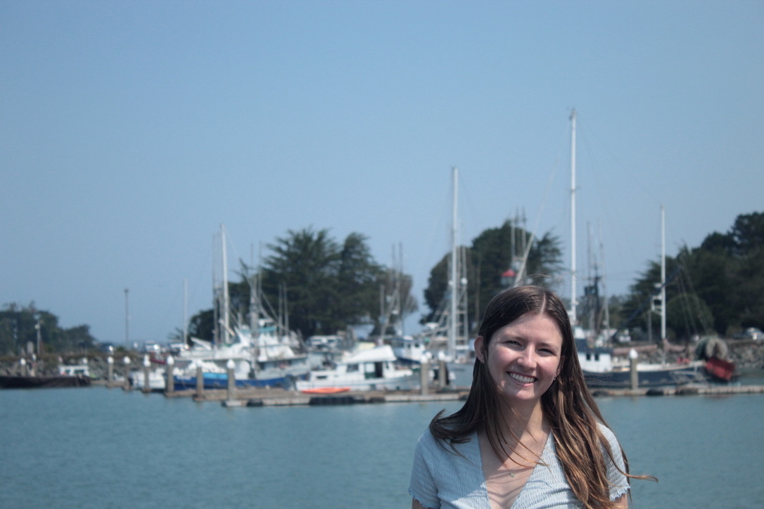 Sara Pickrell '24 stands in front of a harbor on a sunny day