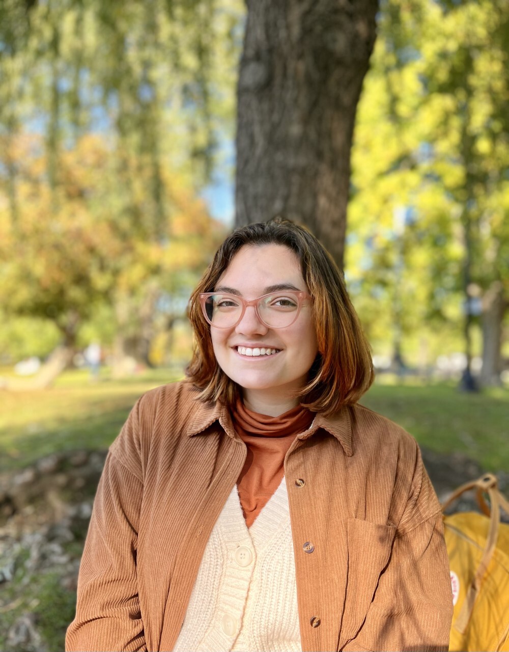 Sabrina Eager sitting outdoors in front of a tree