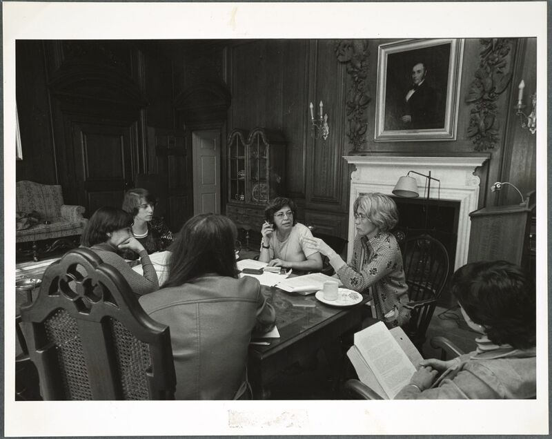A black-and-white photograph of a discussion between several women.