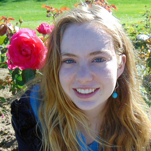 Mia Nelson, the Fall 2019 Historical Accountability Student Research Fellow, sits in front of pink rose bushes.